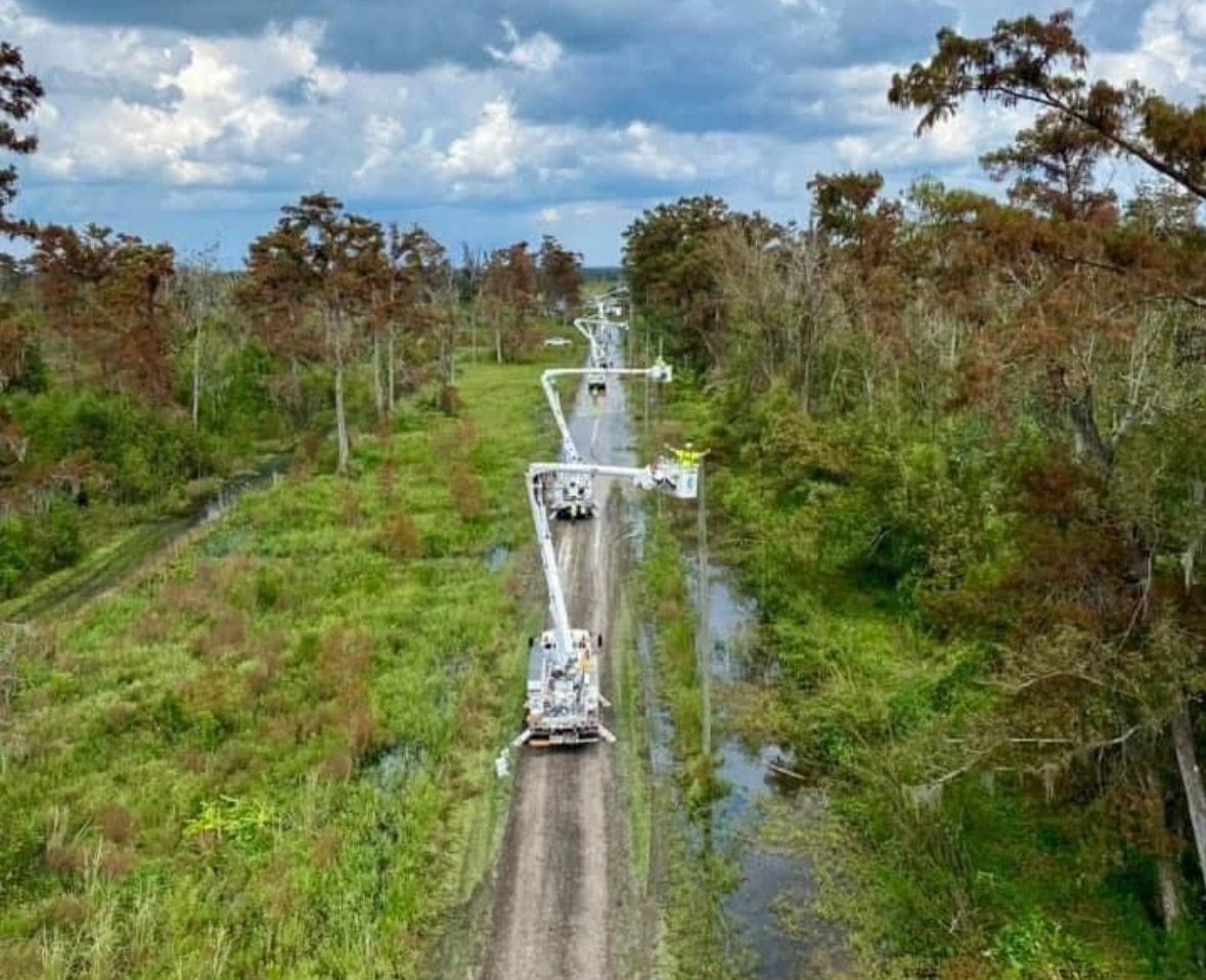 Prime Line Power bucket trucks working a storm-damaged line through a flooded corridor