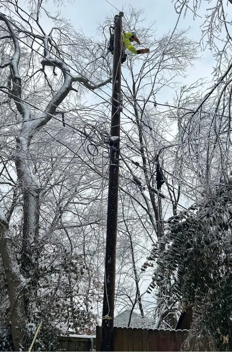 Lineman working an ice-covered pole after an ice storm